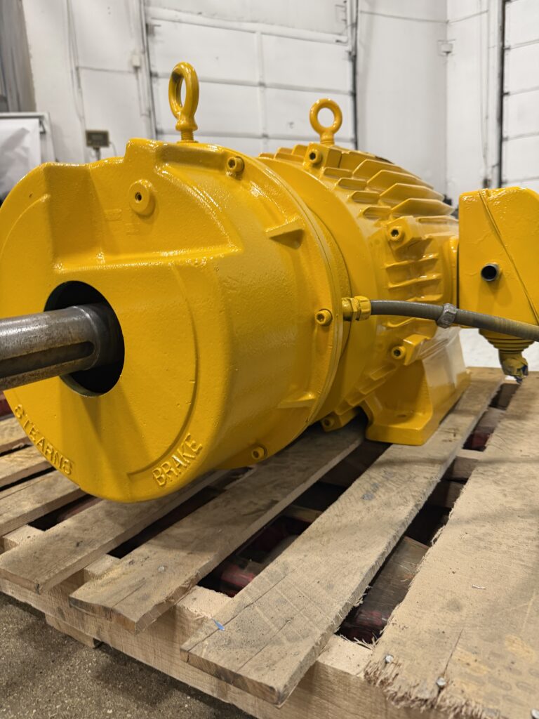 Repaired motor with Stearns brake, repainted yellow, on a pallet ready for delivery